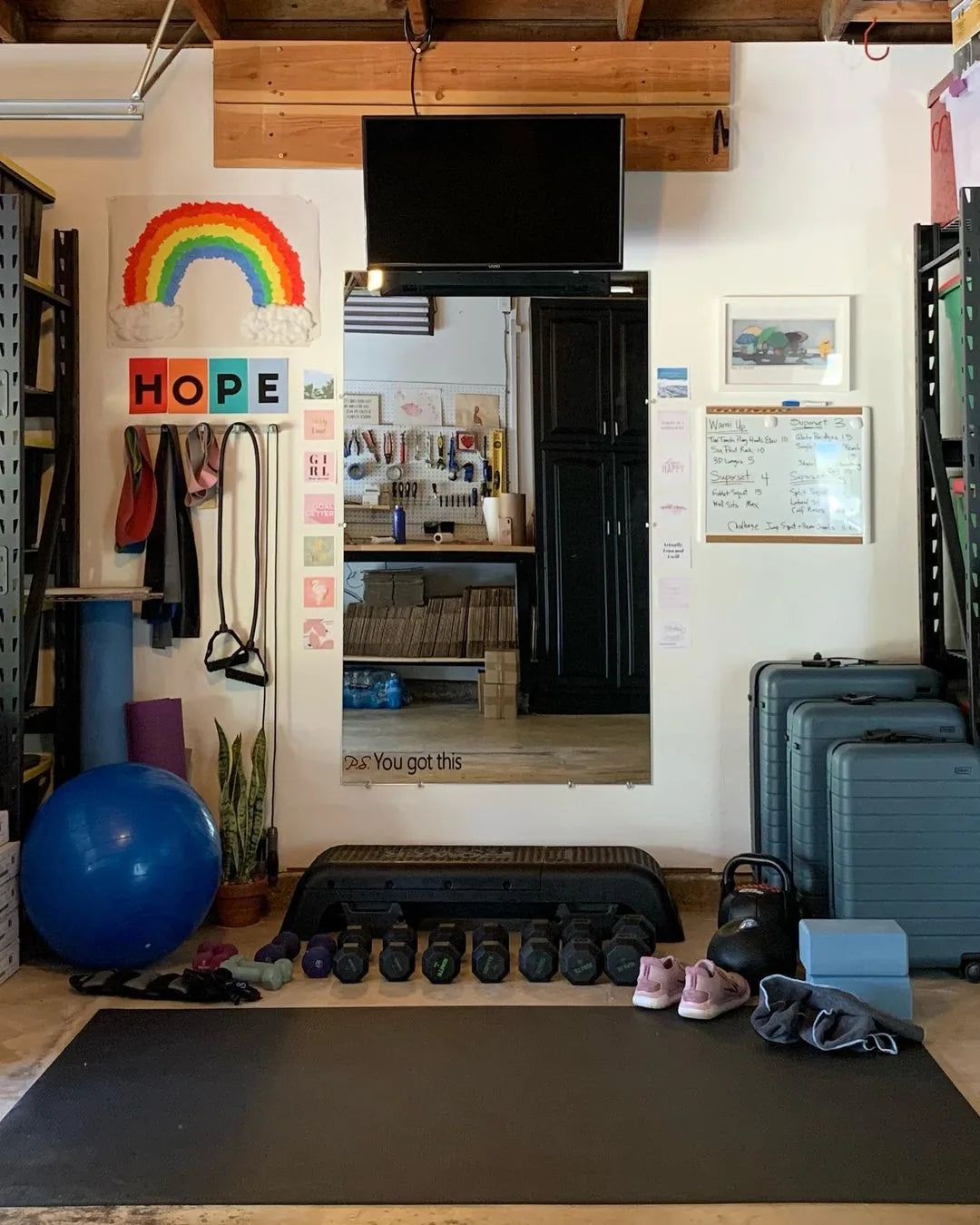Home gym with a large mat covering the floor in front of a dumbbell rack